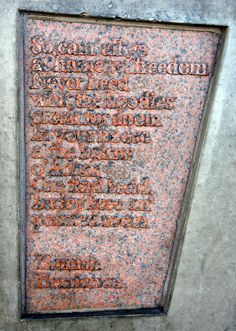 Stone with the following words carved on it: "So, cam' all ye at hame wi' freedom In your hoose a' the bairns o' Adam Can find breid, barley bree an' painted room. Hamish Henderson"