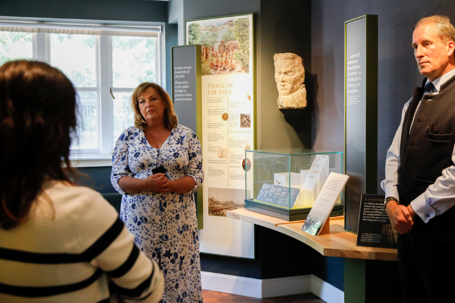 A group of people are given a talk inside a small historic lodge building.