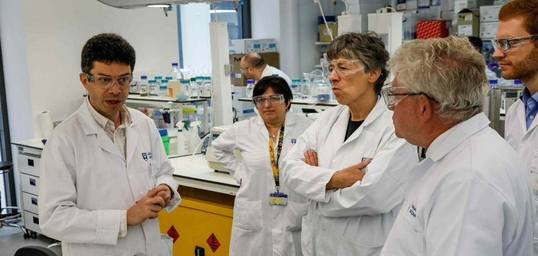 A photo showing Committee members listening to a scientist in a laboratory during the visit to the University of Dundee Life Sciences department as part of its business planning day.