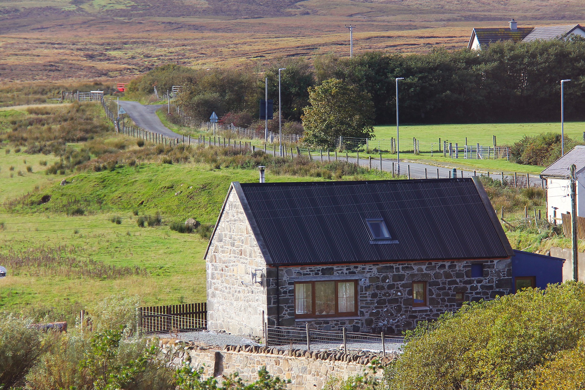 Image of a stone house next to a road in rural Scotland.